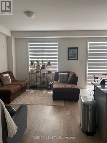Centre Wellington (Fergus) apartment for rent - A living room with a brown couch, a grey armchair, and a small table with a vase on it.