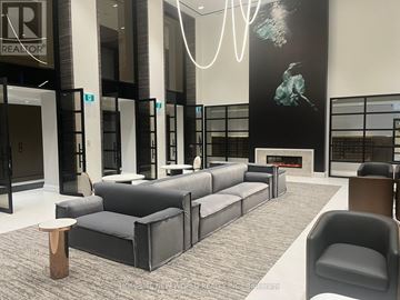 Toronto (Mount Pleasant West) condo for rent - A modern living room with a grey sofa and a wooden stool.