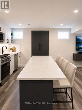 Vaughan (Kleinburg) apartment for rent - A modern kitchen with a long white table and black fridge.