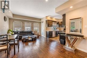 Kitchener townhouse for rent - A well-lit, spacious living room with a large black sofa and a wooden floor.