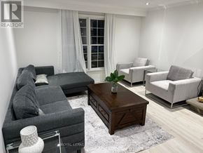 Oakville (Mo Morrison) apartment for rent - A living room with a grey sofa, a wooden coffee table, and a white chair.