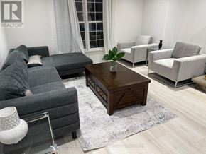 Oakville (Mo Morrison) apartment for rent - A living room with a grey couch, a wooden coffee table, and a white lamp.