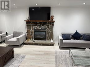 Oakville (Mo Morrison) apartment for rent - A living room with a stone fireplace and a flat screen TV mounted above it.