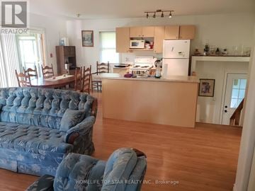 Marmora And Lake (Marmora Ward) apartment for rent - A blue sofa sits in a living room with a kitchen in the background.