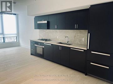 Toronto (Englemount-Lawrence) condo for rent - A kitchen with black cabinets and a marble countertop.