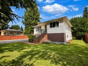 Delta apartment for rent - A house with a brown roof and a white wall is surrounded by a green lawn.