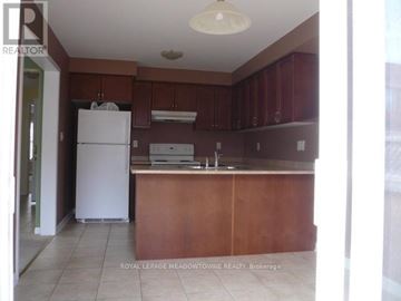 Milton (Be Beaty) apartment for rent - A kitchen with brown cabinets and a white refrigerator.