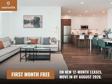 Chilliwack apartment for rent - A living room with a couch, coffee table, and kitchen area in the background with a sign offering a free first month on new 12-month leases.