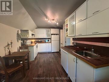 New Tecumseth (Alliston) triplex for rent - A kitchen with white cabinets and a wooden table.