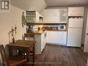New Tecumseth (Alliston) triplex for rent - A kitchen with white cabinets and a wooden table.
