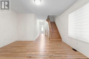 Richmond Hill apartment for rent - A spacious room with wooden floors and a staircase leading to another room.