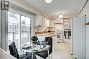 Newmarket (Bristol-London) apartment for rent - A modern kitchen with a glass table and chairs, a refrigerator, and a view of the backyard through the sliding glass doors.