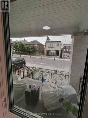 Toronto (Oakwood Village) duplex for rent - A view from a window looking out at a street with buildings and a car.