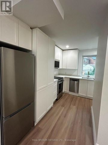 Toronto (Oakwood Village) duplex for rent - A kitchen with white cabinets and a stainless steel refrigerator.