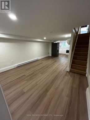 Toronto (Oakwood Village) duplex for rent - A spacious room with wooden flooring and a staircase on the right side.