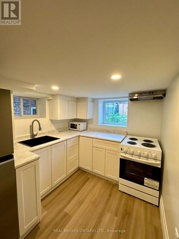Toronto (Oakwood Village) duplex for rent - A kitchen with white cabinets and a stove top oven.