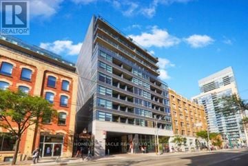 Toronto (Kensington-Chinatown) condo for rent - A modern building with a glass facade is situated in front of a red brick building.