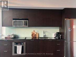 Toronto (Kensington-Chinatown) condo for rent - A kitchen with brown cabinets and a white refrigerator.