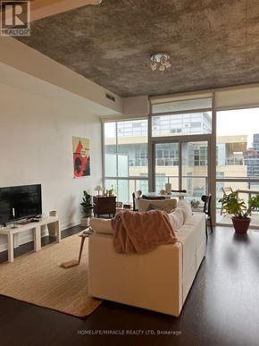 Toronto (Kensington-Chinatown) condo for rent - A living room with a white couch and a television.