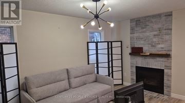 Orangeville apartment for rent - A grey couch is in front of a fireplace in a living room.