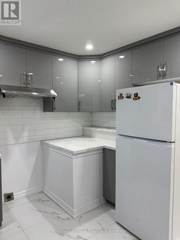 Brampton (Avondale) apartment for rent - A white refrigerator with magnets on the door stands in a kitchen with white cabinets and a white countertop.