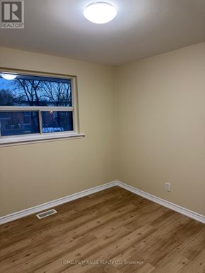 Brampton (Avondale) apartment for rent - A room with wooden flooring and a window showing a view of trees outside.