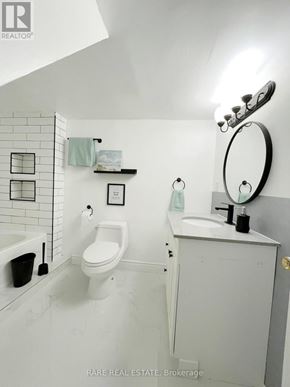 Wasaga Beach apartment for rent - A white bathroom with a toilet, sink, and mirror.