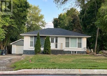 Mississauga (Streetsville) apartment for rent - A house with a grey roof and white walls is surrounded by trees.