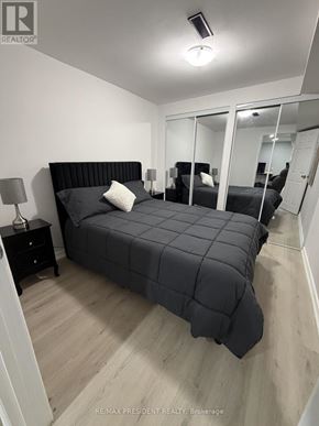 Mississauga (Malton) apartment for rent - A bedroom with a large bed and a nightstand with a lamp.