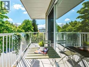 Vancouver apartment for rent - A balcony with a table and chairs overlooking a lush green area.