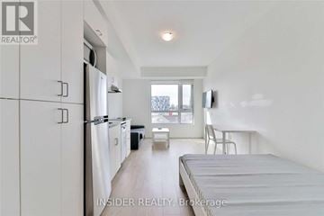 Oshawa (Samac) condo for rent - A white bedroom with a bed, chair, and a small table.