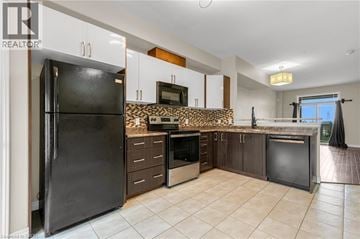 Grimsby townhouse for rent - A black refrigerator stands in a kitchen with white cabinets and a stone backsplash.
