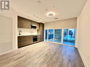 Toronto (Mount Pleasant West) condo for rent - A spacious kitchen with wooden cabinets and a large window overlooking the city.