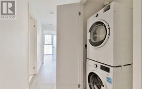 Toronto (Waterfront Communities) condo for rent - A white washing machine is stacked on top of another in a narrow hallway.