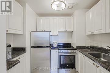 Toronto (The Beaches) multi-family for rent - A kitchen with white cabinets and a black stove top.