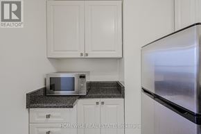Toronto (The Beaches) multi-family for rent - A kitchen with a microwave on a counter and a refrigerator.