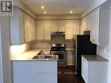 Vaughan (Patterson) townhouse for rent - A kitchen with white cabinets and a black refrigerator.
