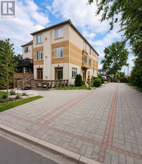 Richmond Hill (Langstaff) apartment for rent - A large two-story building with a balcony and a driveway in front.