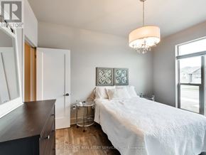 Port Colborne (Sugarloaf) apartment for rent - A bedroom with a white bed and a chandelier hanging from the ceiling.
