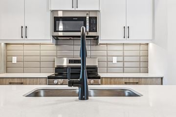 Edmonton apartment for rent - A modern kitchen with a stainless steel sink and a microwave above the stove.