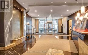 Toronto (Waterfront Communities) condo for rent - A hallway with a marble floor and a glass door leading to a parking garage.