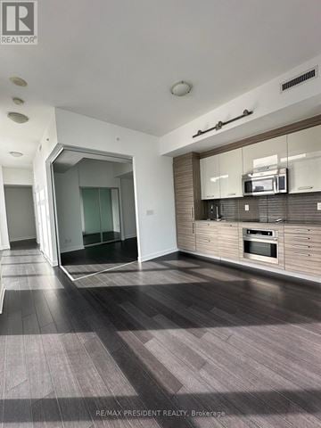 Toronto (Kensington-Chinatown) condo for rent - A modern kitchen with a wooden cabinet and a glass-fronted cabinet.