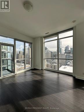 Toronto (Kensington-Chinatown) condo for rent - A large, empty room with a view of the cityscape outside the windows.