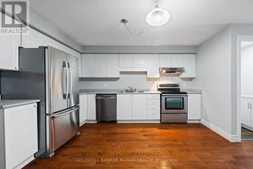 Orangeville townhouse for rent - A kitchen with white cabinets and a wooden floor.