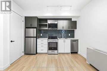Hamilton (Corktown) multi-family for rent - A kitchen with white cabinets and stainless steel appliances.