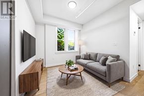 Hamilton (Corktown) multi-family for rent - A living room with a grey couch, a wooden coffee table, and a flat screen TV mounted on the wall.