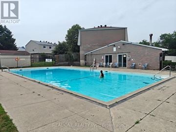 Mississauga (Mississauga Valleys) townhouse for rent - A person is swimming in a pool with a house in the background.