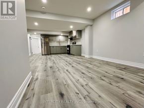 Bradford West Gwillimbury (Bradford) apartment for rent - A spacious room with wooden flooring and a kitchen area in the background.