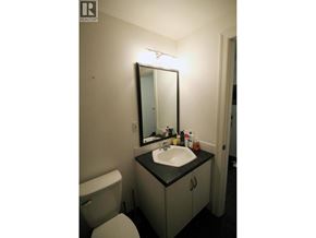 Coquitlam apartment for rent - A bathroom with a toilet, sink and mirror.