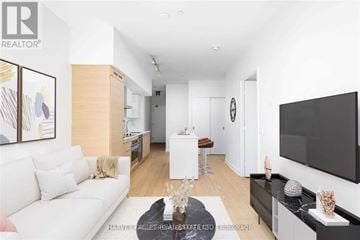 Toronto (Niagara) house for rent - A living room with a white couch and a flat screen TV mounted on the wall.